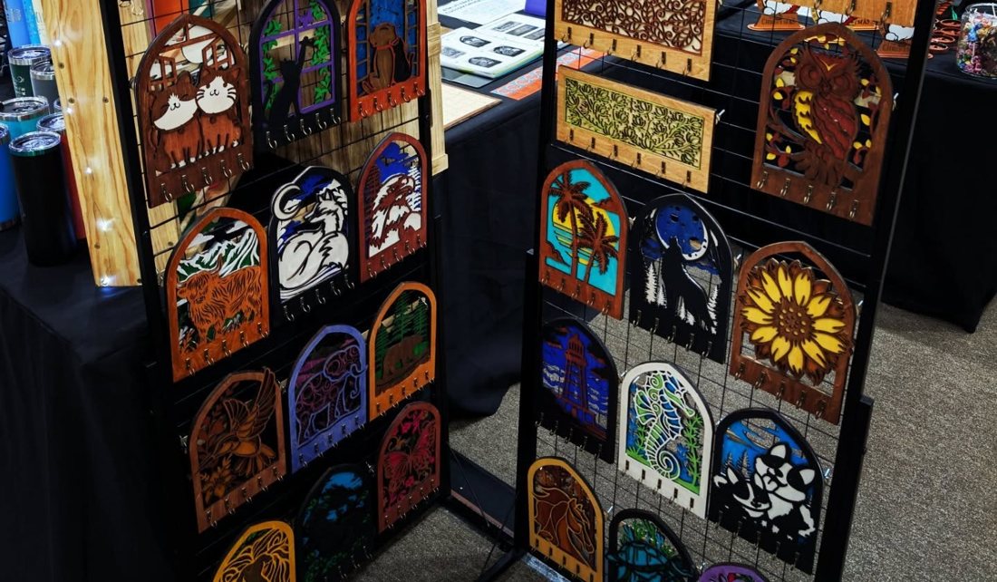 Racks of three-layer laser-cut wood key holders: wildlife, pets, sunflowers and more